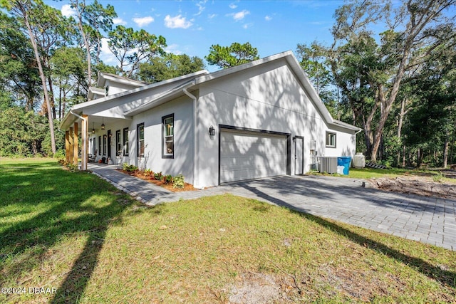 view of side of property featuring central air condition unit, a garage, and a lawn