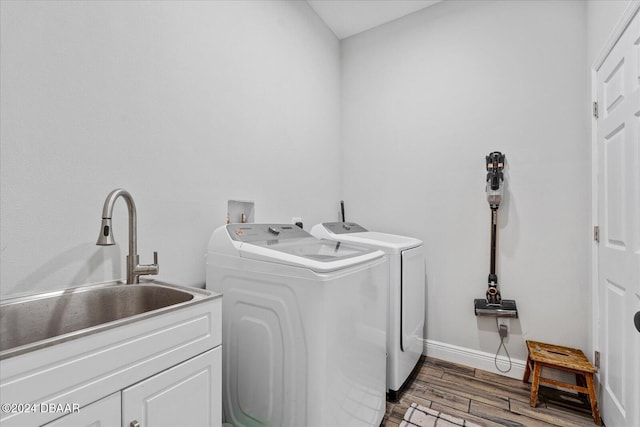 laundry area featuring washing machine and clothes dryer, wood-type flooring, cabinets, and sink