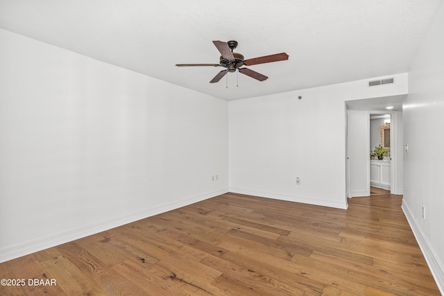 empty room with light wood-style floors, baseboards, visible vents, and ceiling fan