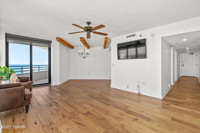 living room with ceiling fan with notable chandelier, a water view, visible vents, baseboards, and light wood-type flooring