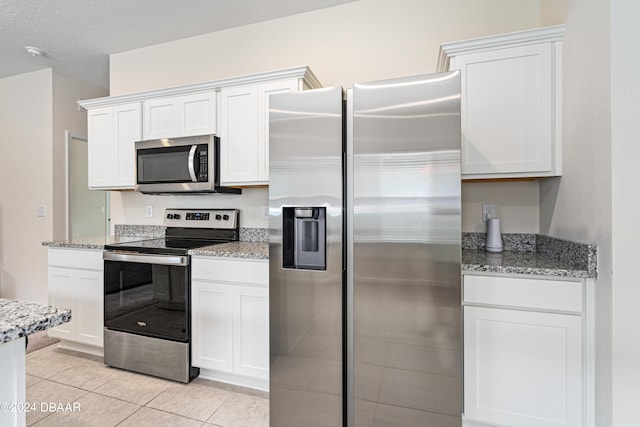 kitchen featuring appliances with stainless steel finishes, light tile patterned floors, and white cabinets