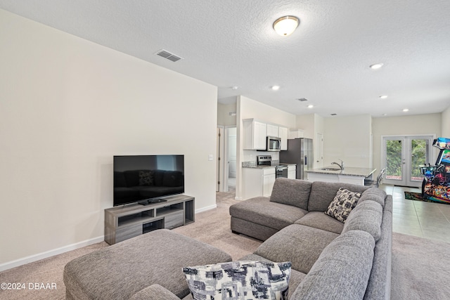 carpeted living room with sink, french doors, and a textured ceiling