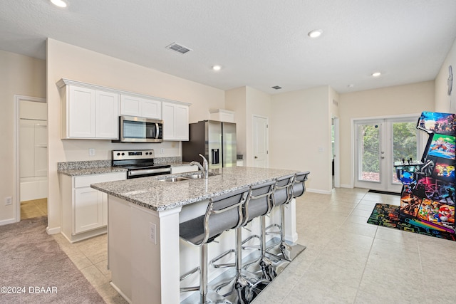 kitchen featuring appliances with stainless steel finishes, sink, an island with sink, and white cabinets