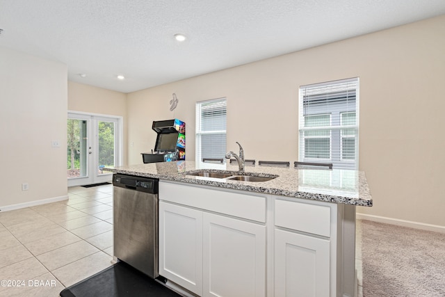 kitchen featuring light tile patterned flooring, sink, light stone countertops, white cabinets, and dishwasher