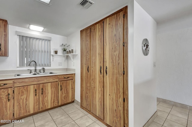 kitchen with light countertops, light tile patterned floors, visible vents, and a sink