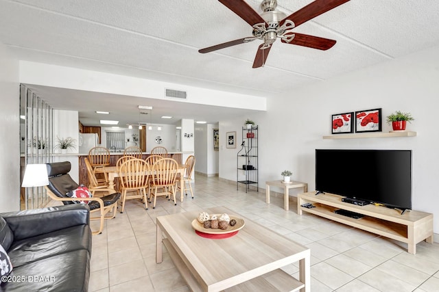 living area featuring light tile patterned floors, a ceiling fan, a textured ceiling, and visible vents