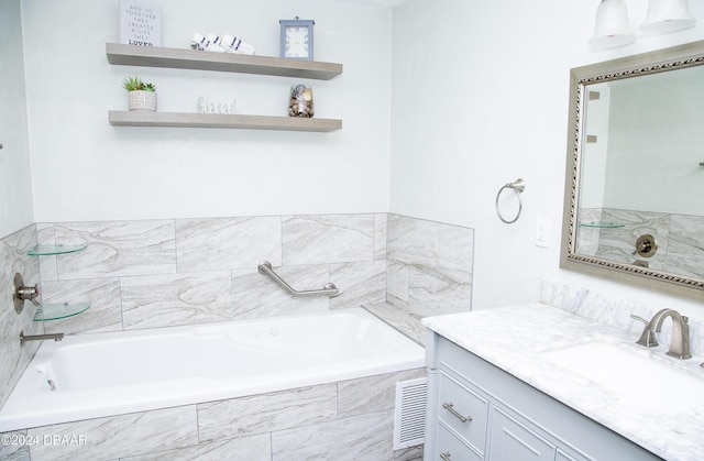 bathroom with vanity and tiled tub