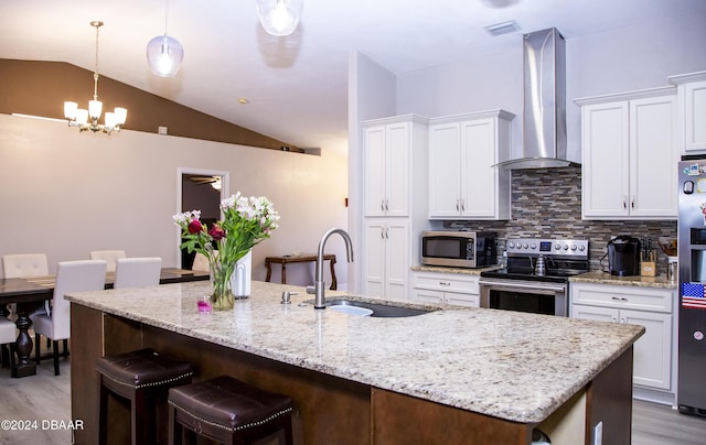 kitchen with lofted ceiling, wall chimney range hood, sink, tasteful backsplash, and stainless steel appliances