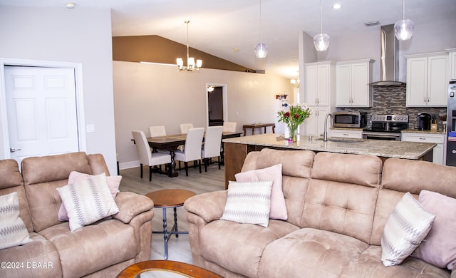 living room featuring light hardwood / wood-style floors, lofted ceiling, sink, and an inviting chandelier