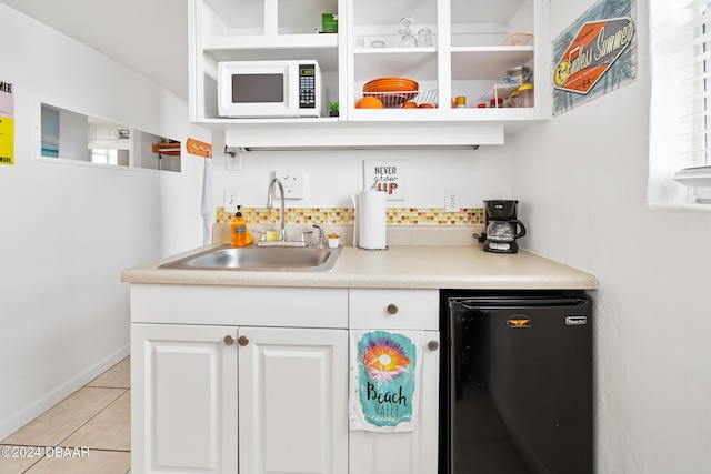 bar with black refrigerator, white cabinetry, sink, and light tile patterned floors