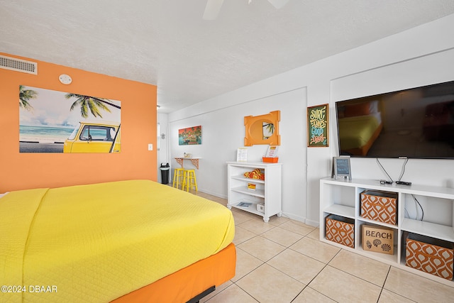 tiled bedroom featuring ceiling fan and a textured ceiling