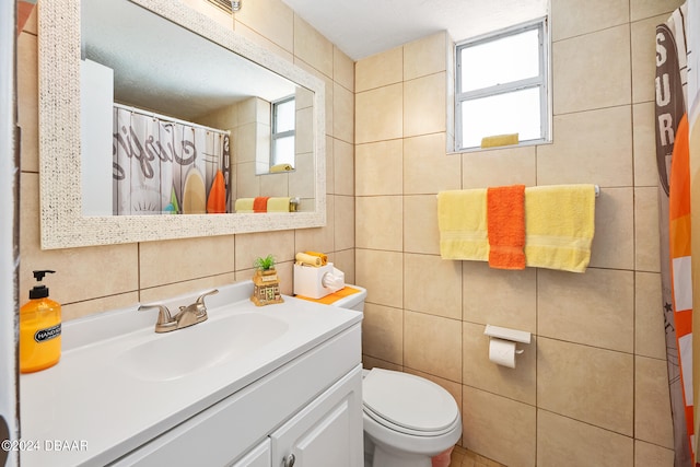 bathroom featuring toilet, tile walls, a textured ceiling, vanity, and walk in shower