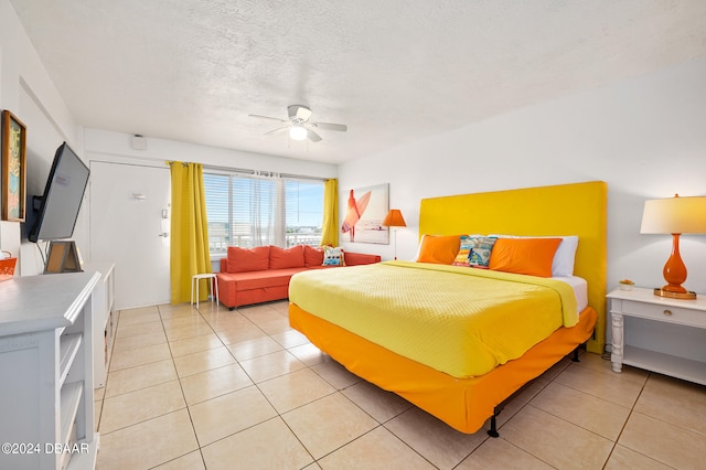 bedroom with a textured ceiling, ceiling fan, and light tile patterned flooring