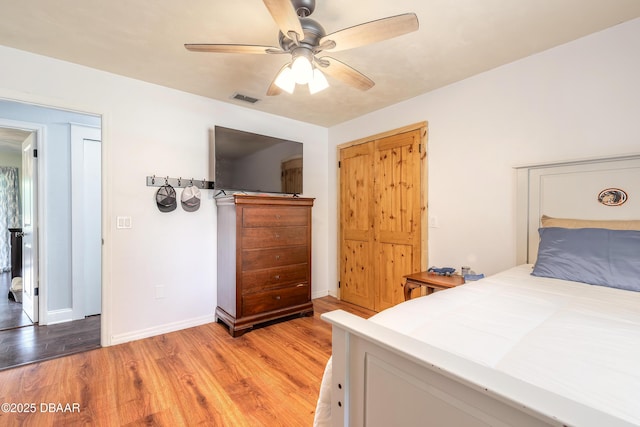 bedroom with baseboards, a ceiling fan, light wood-style flooring, and visible vents