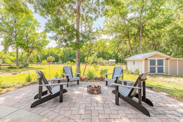 view of patio with fence, an outbuilding, a shed, and an outdoor fire pit