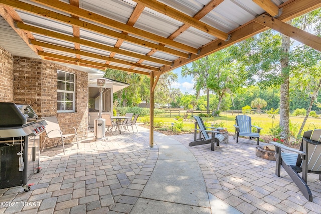 view of patio with a fire pit, fence, and a grill