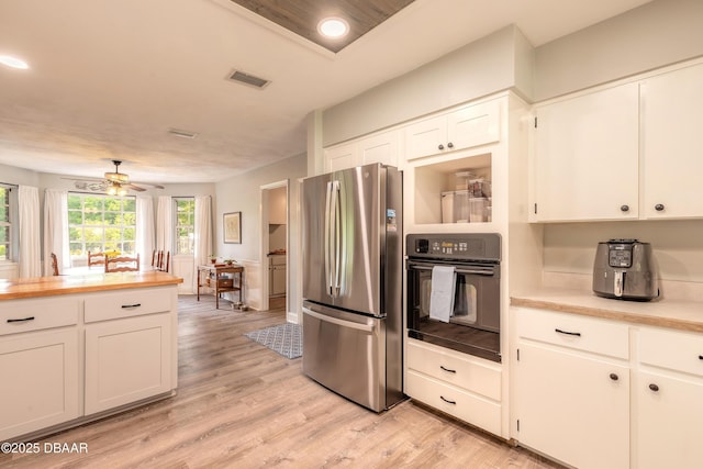 kitchen with oven, light wood-style floors, light countertops, freestanding refrigerator, and visible vents