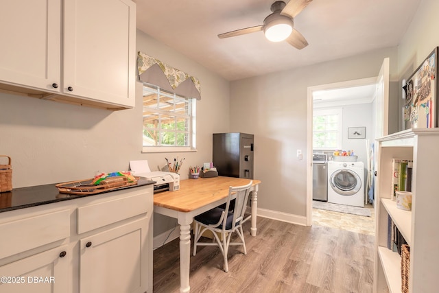 interior space featuring laundry area, ceiling fan, light wood finished floors, baseboards, and washer and clothes dryer