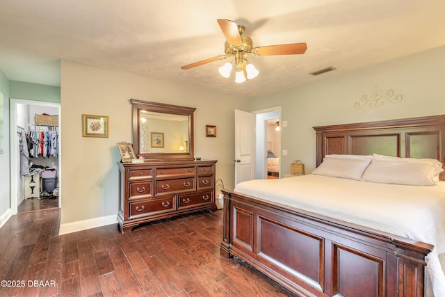 bedroom featuring visible vents, baseboards, dark wood-style floors, a spacious closet, and a ceiling fan
