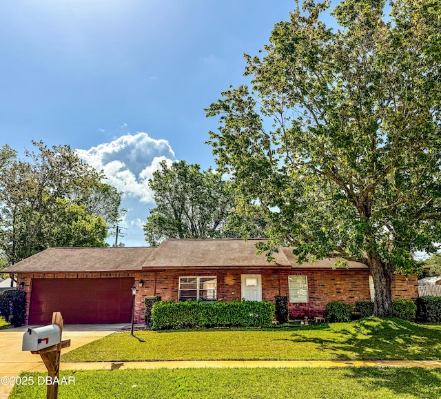 single story home with brick siding, concrete driveway, a garage, and a front yard