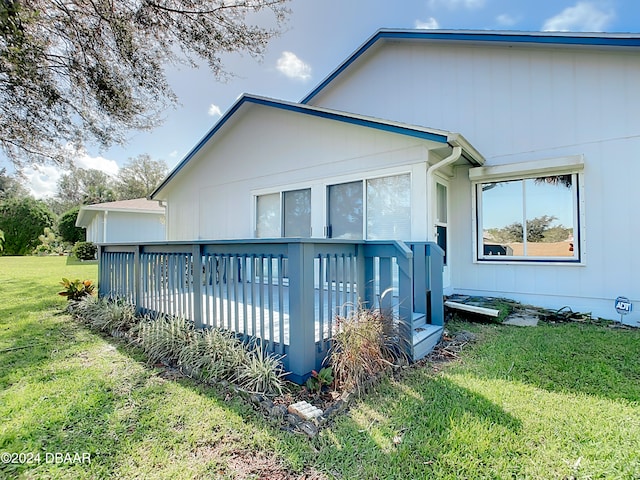 rear view of house featuring a wooden deck and a yard