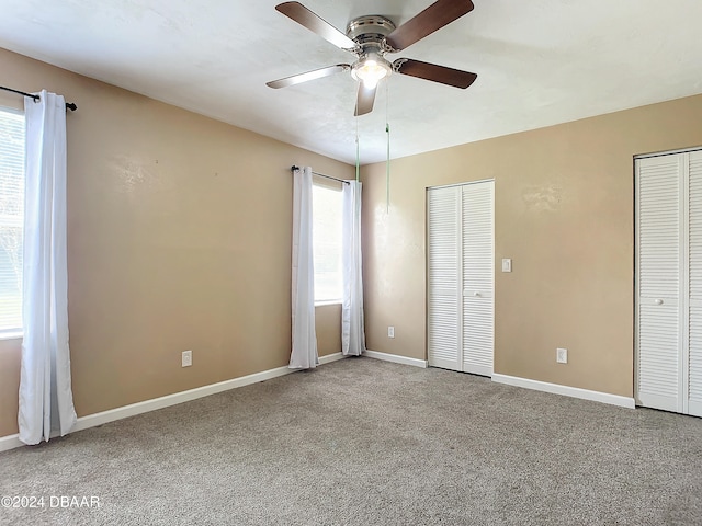 unfurnished bedroom with carpet, two closets, and ceiling fan