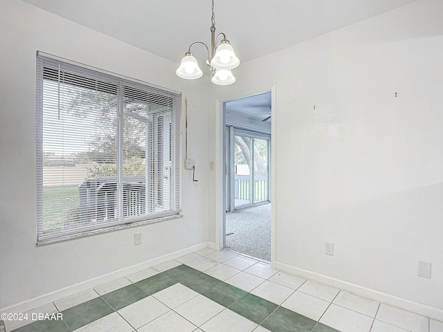 spare room with an inviting chandelier and light tile patterned floors