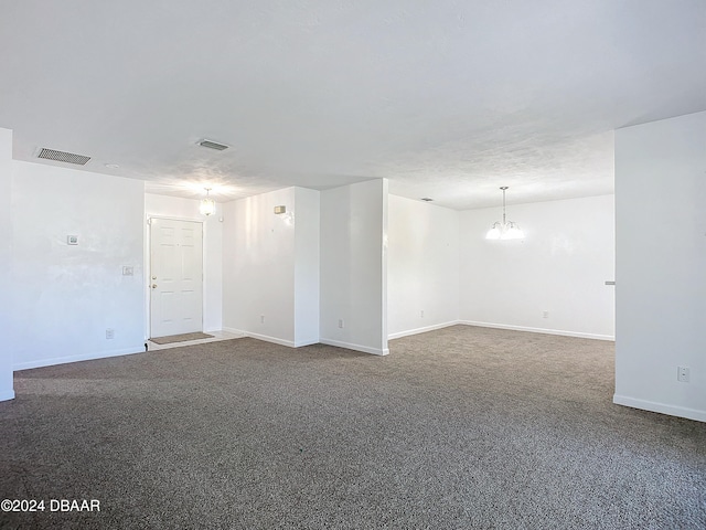 carpeted spare room featuring a notable chandelier