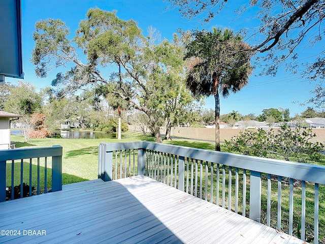 wooden deck featuring a lawn and a water view