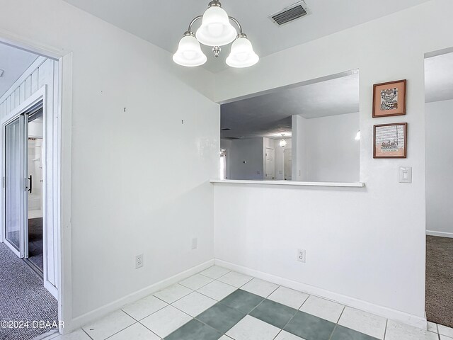 tiled empty room with a chandelier