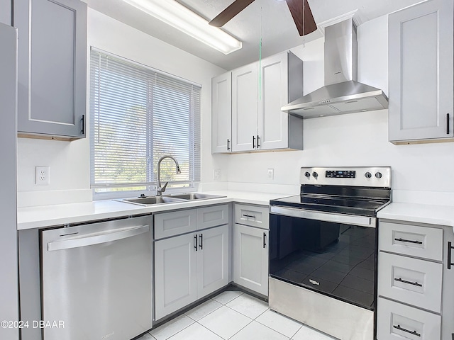 kitchen with stainless steel appliances, light tile patterned flooring, sink, ceiling fan, and wall chimney range hood