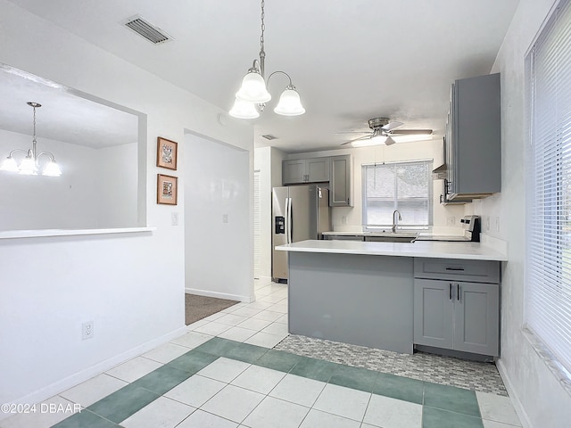 kitchen featuring stainless steel fridge, range, light tile patterned floors, gray cabinets, and kitchen peninsula