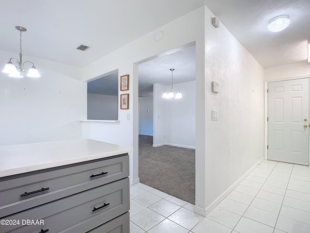 interior space with gray cabinets, light colored carpet, a notable chandelier, and decorative light fixtures