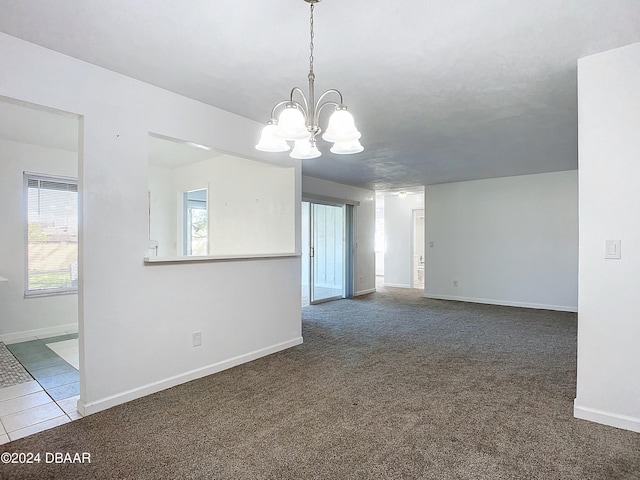 empty room with an inviting chandelier and dark carpet