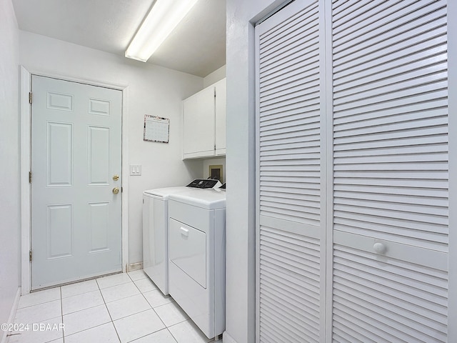 clothes washing area featuring light tile patterned floors, cabinets, and washer and dryer