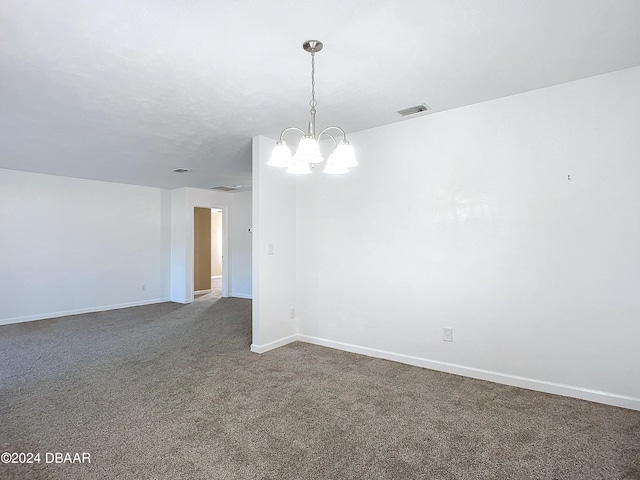 empty room featuring a chandelier and dark carpet