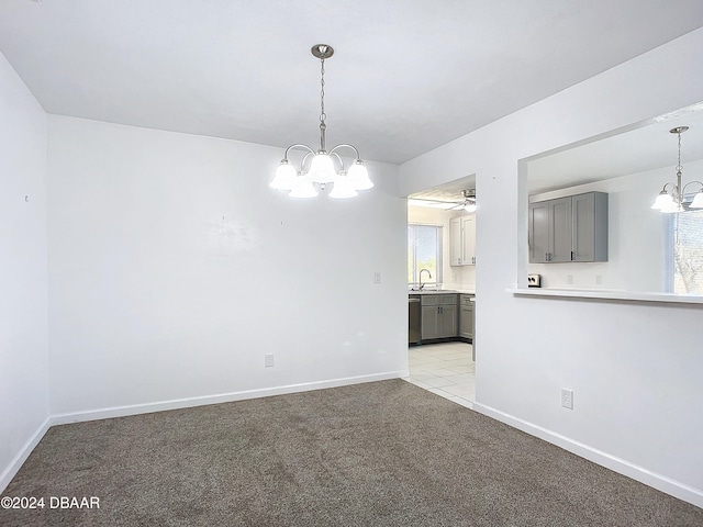 unfurnished room featuring a wealth of natural light, light colored carpet, and ceiling fan with notable chandelier