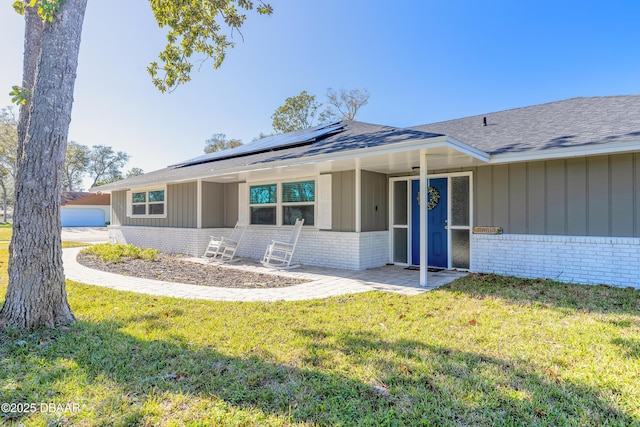 ranch-style house with solar panels, a front lawn, and a garage