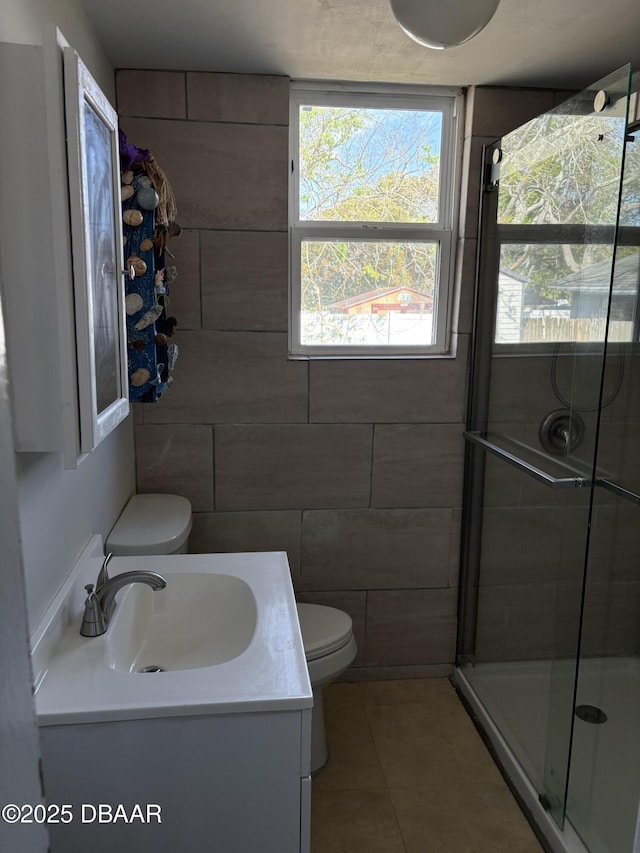 full bathroom featuring tile walls, toilet, a stall shower, vanity, and tile patterned flooring