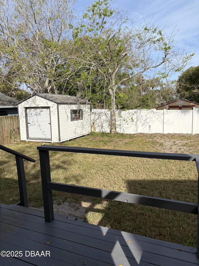 view of yard featuring a fenced backyard, a storage unit, a deck, and an outdoor structure