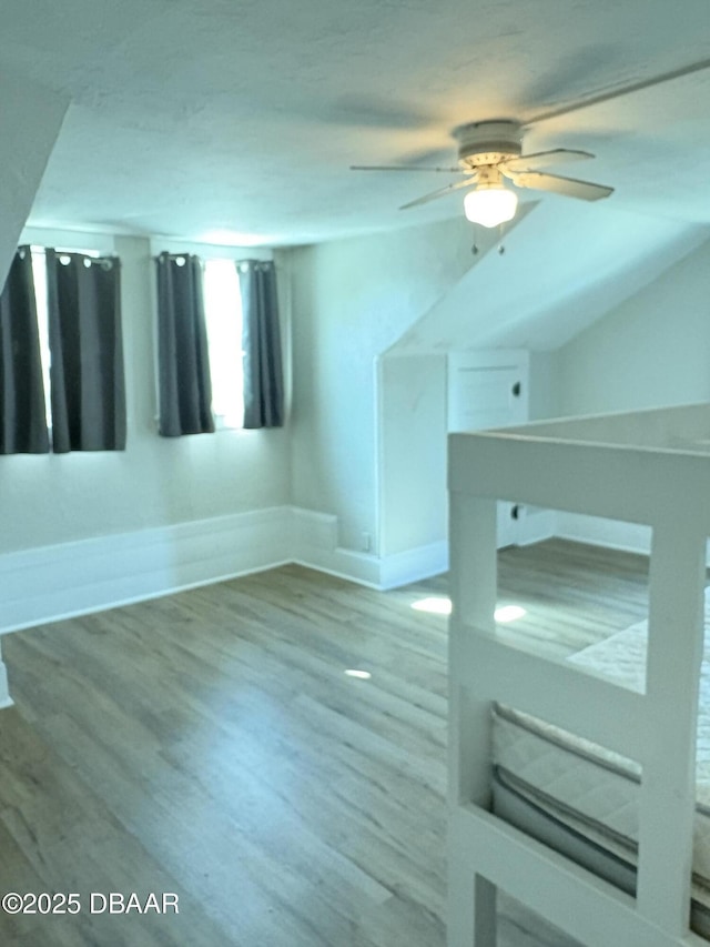 bonus room with a ceiling fan, baseboards, and wood finished floors