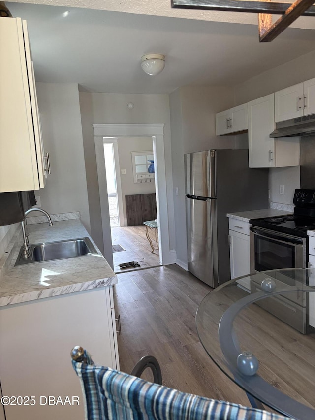 kitchen featuring stainless steel appliances, light countertops, white cabinetry, a sink, and under cabinet range hood