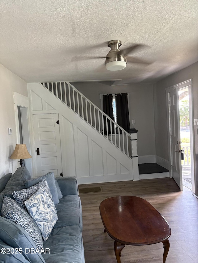 living area featuring a textured ceiling, stairs, and wood finished floors