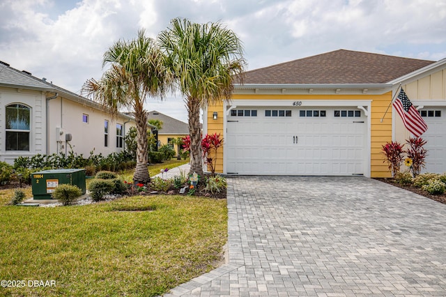 single story home with decorative driveway, a front lawn, and roof with shingles