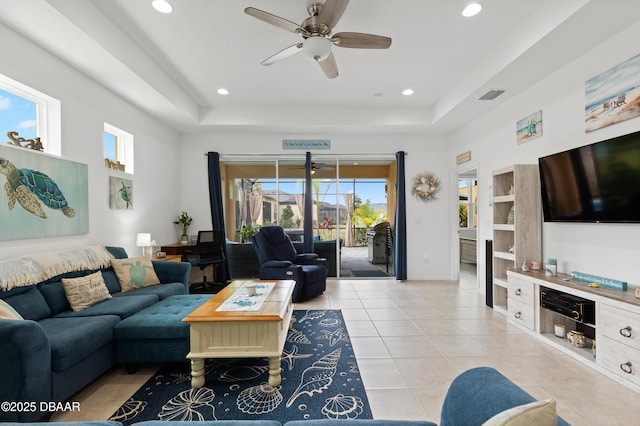 living area with light tile patterned floors, visible vents, recessed lighting, and a tray ceiling