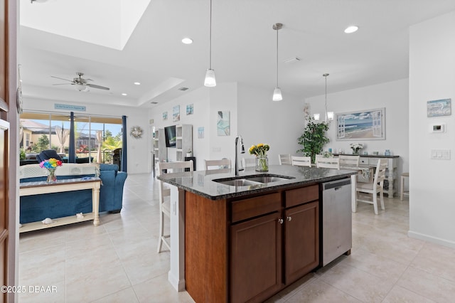 kitchen with recessed lighting, dark stone countertops, a kitchen breakfast bar, stainless steel dishwasher, and a sink