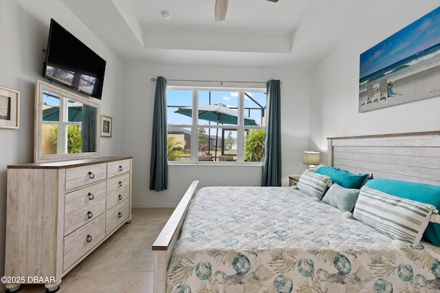 bedroom with ceiling fan, a tray ceiling, baseboards, and light tile patterned flooring