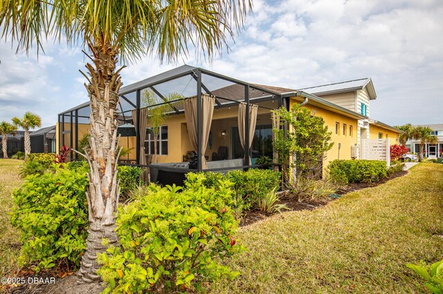 back of property featuring a lawn and a lanai