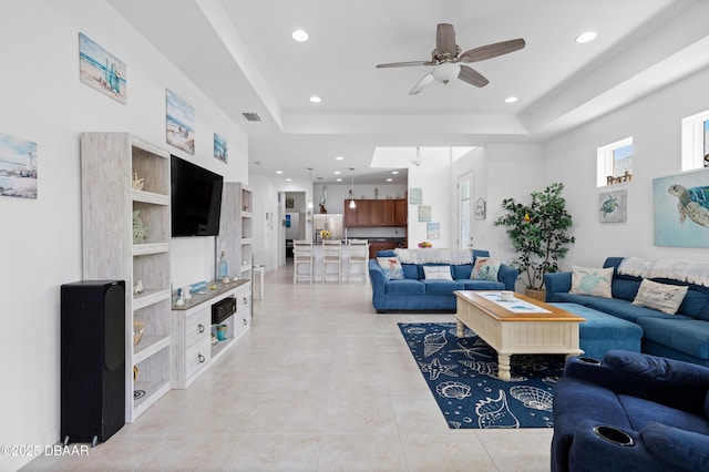 living room with light tile patterned floors, visible vents, a raised ceiling, and recessed lighting