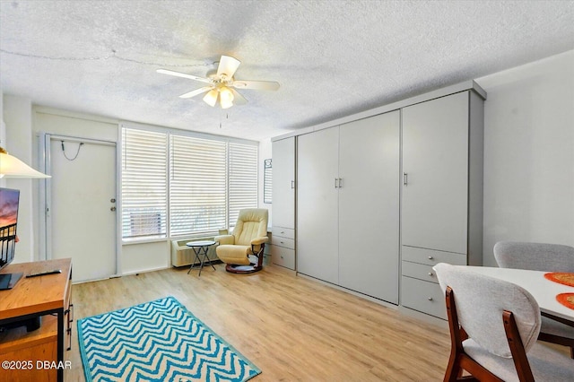 living area with light wood-type flooring, a textured ceiling, and ceiling fan